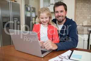 Father and daughter working on laptop