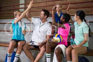 Volleyball coach giving high five to female players