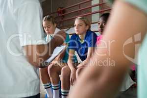 Volleyball coach talking to female players