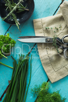 Various herbs, scissors and napkin on wooden table