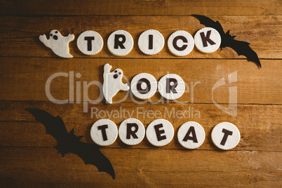 Cookies with trick or treat text by spooky decorations on table