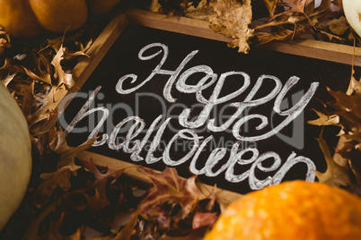 Happy halloween text on slate with autumn leaves