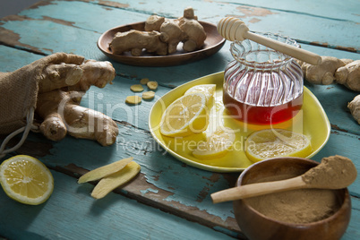 Lemon and ginger with honey jar on weathered table