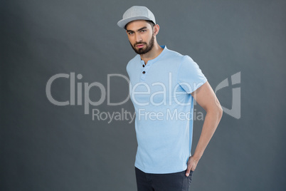 Handsome man posing with hands in pocket against grey background