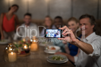 Happy friends taking selfie with mobile phone
