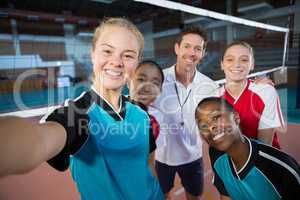 Male coach and volleyball players taking selfie