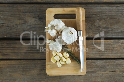 Garlics, rosemary and knife on chopping board