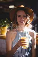 Portrait of smiling young woman holding fresh juice glass