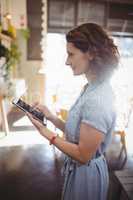 Side view of female customer using tablet at cafe