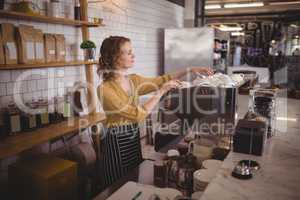 Young waitress arranging cups at counter