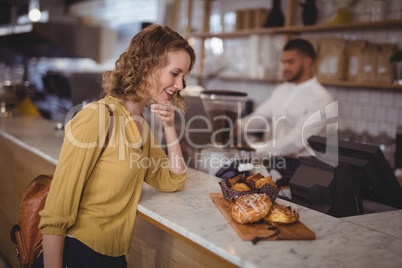 Smiling young female cutomer looking at food in serving board on counter