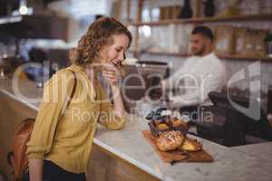 Smiling young female cutomer looking at food in serving board on counter