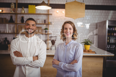 Portrait of smiling young friends standing with arms crossed