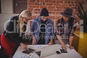 Young creative team using digital tablets while standing at coffee shop