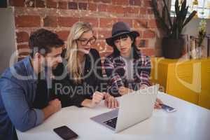 Young creative team using laptop while sitting at coffee shop