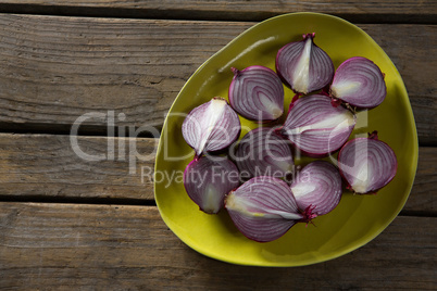 Halved onions in a plate on wooden table