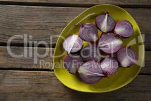 Halved onions in a plate on wooden table
