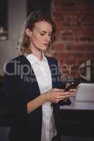 Confident young female editor using smartphone at coffee shop