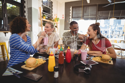 Cheerful young friends sharing food at coffee shop