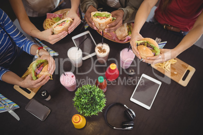 High angle view of friends holding fresh food at coffee shop