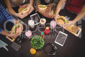 High angle view of friends holding fresh food at coffee shop