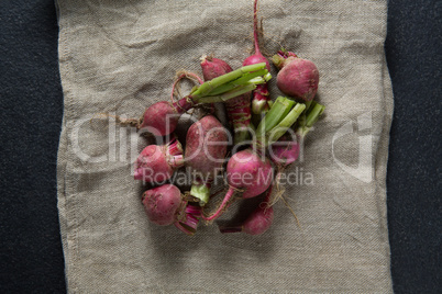 Overhead view of red radishes on burlap