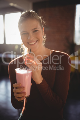 Portrait of smiling young woman with milkshake at cafe