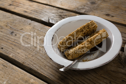 Granola bar in bowl on wooden table