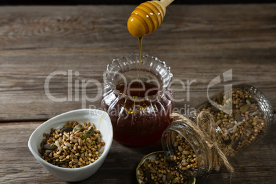 Breakfast cereals and jar of honey on wooden table
