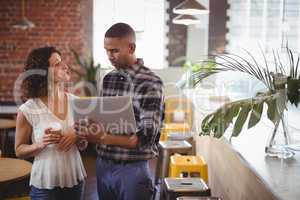 Young friends talking while holding laptop and coffee