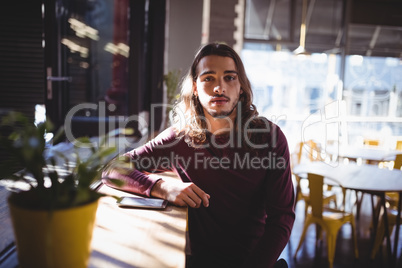 Portrait of young man with long hair sitting at coffee shop