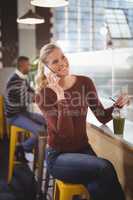 Happy beautiful blond woman talking on celllphone at coffee shop