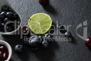 Slice of lemon and spoon with blueberries on black background