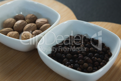 Nutmegs and black pepper seeds in chopping board