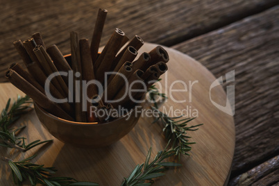 Cinnamon sticks and rosemary on a chopping board