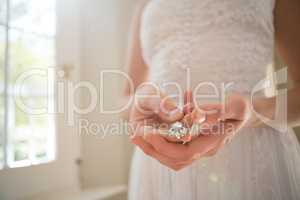 Midsection of bride holding diamond earring at home