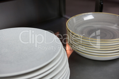 Stack of plates arranged on shelf