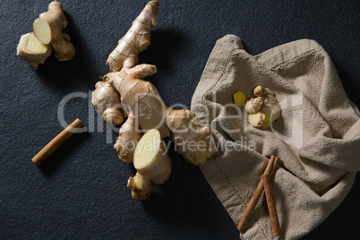 Ginger and cinnamon with napkin on black background