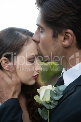 Groom kissing on bride forehead