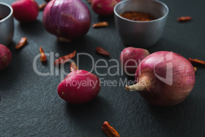 Onions and red pepper flakes on black background