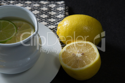 Tea cup with lemon on black background