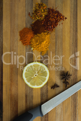 Various spices with lemon slice and knife on chopping board