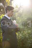 Confident bridegroom adjusting necktie in park