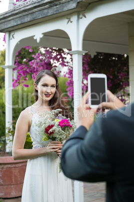 Cropped hands of bridegroom photographing bride at park