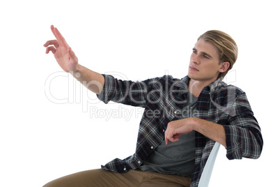 Businessman touching imaginary interface while sitting on chair