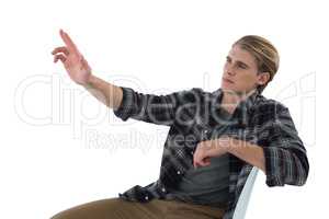 Businessman touching imaginary interface while sitting on chair