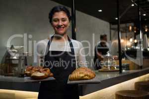 Portrait of happy waitress holding breakfast