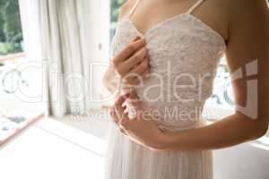 Midsection of bride trying on wedding dress