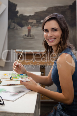 Portrait of smiling woman painting on drawing book