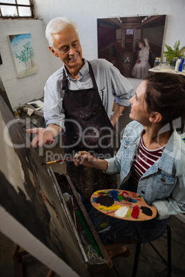 Senior man interacting while artist painting on canvas